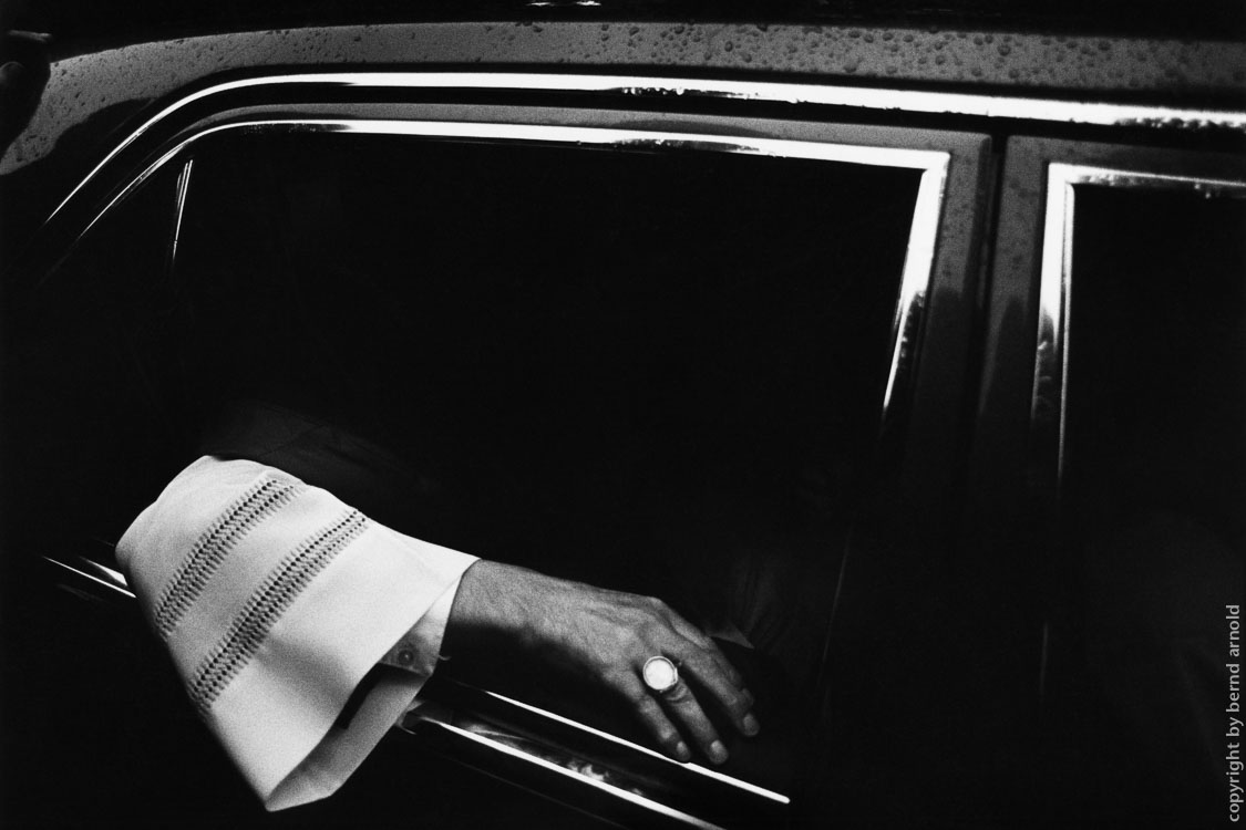 Kardinal hält Arm aus seinem Dienstwagen mit Bischofsring an seiner Hand – Dokumentarfotografie